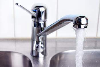 A kitchen sink with water running from a faucet