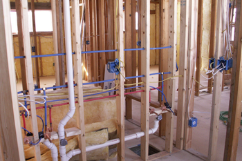 A house is being built with a lot of pipes and wires.