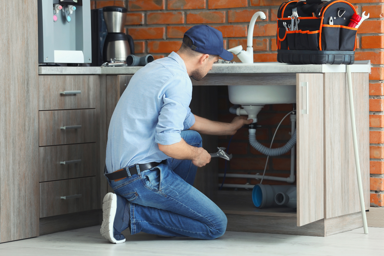 A plumber is fixing a sink in a kitchen.