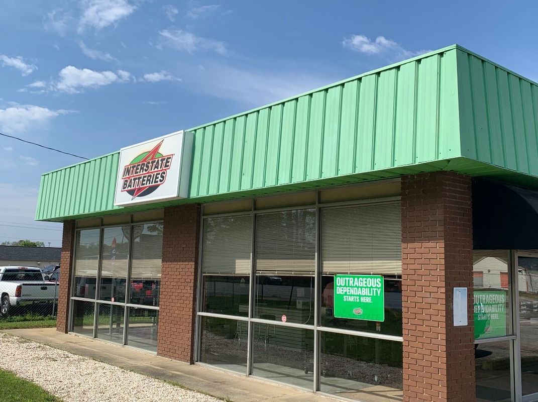 A small brick building with a green awning. A sign above reads 