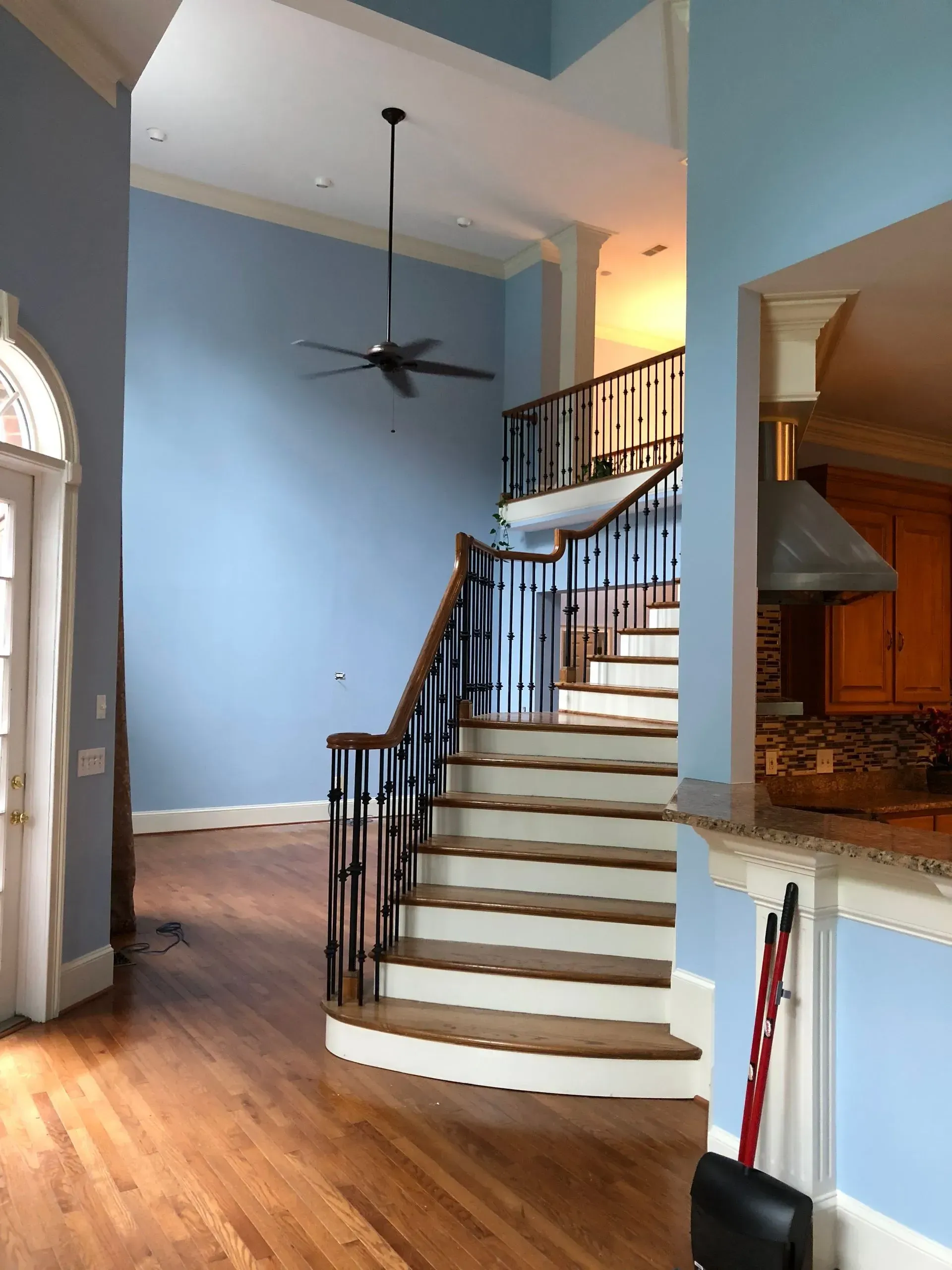 A two-story entryway with blue walls, a curved staircase, and hardwood floors.