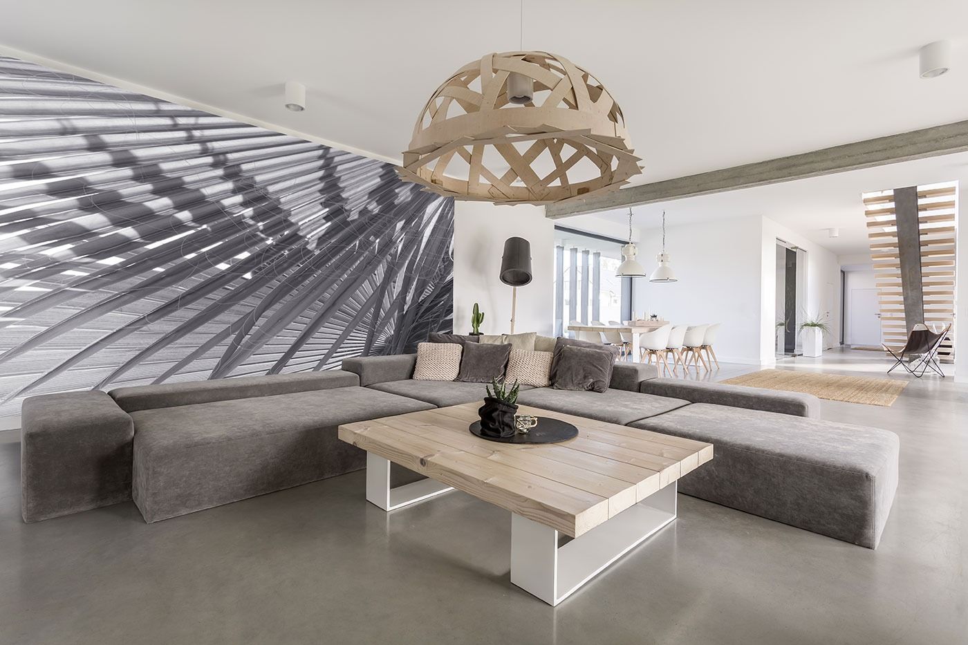 A living room with a large sectional couch and a wooden coffee table.