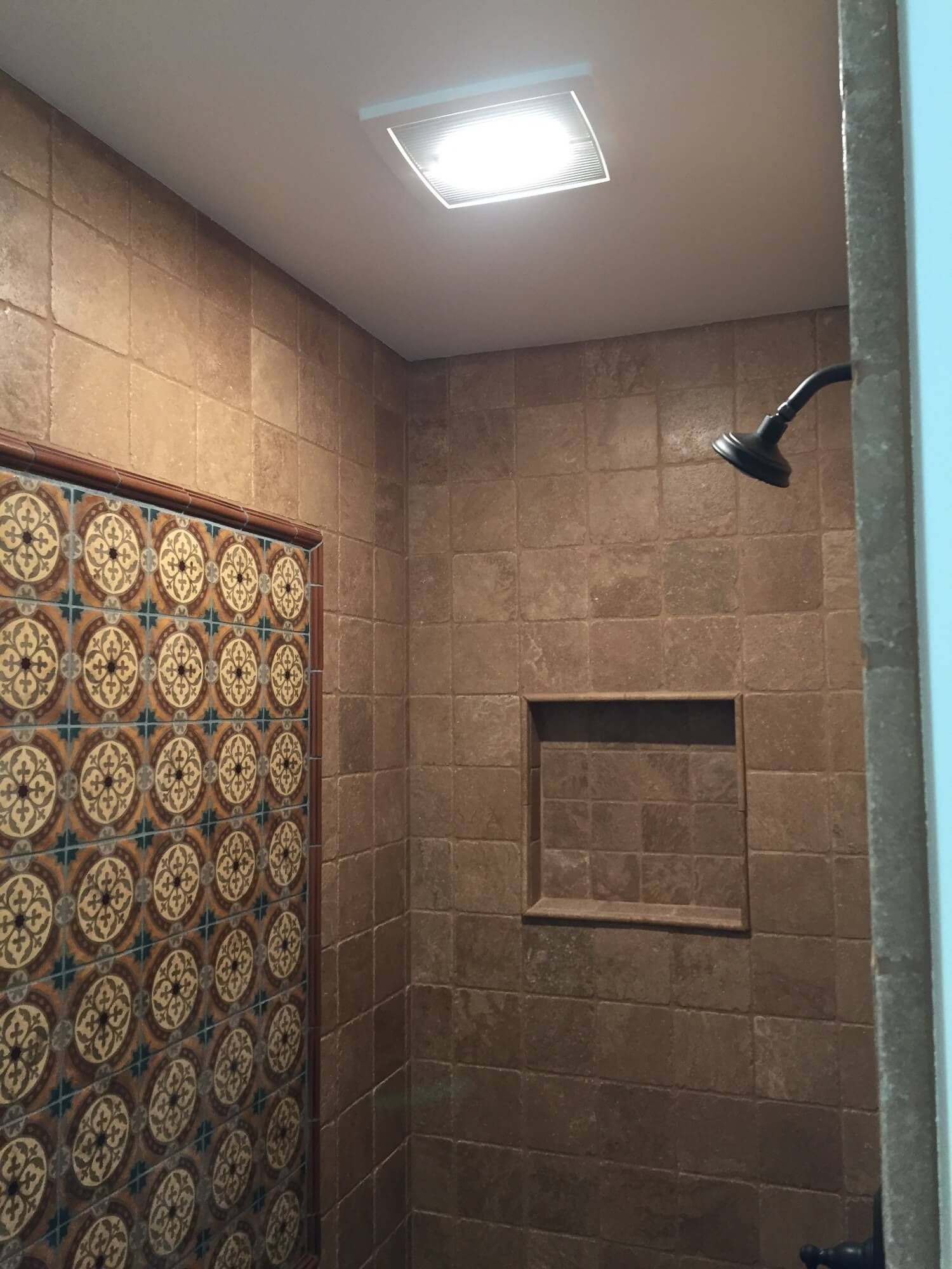 A shower with a tiled wall and a shower head.