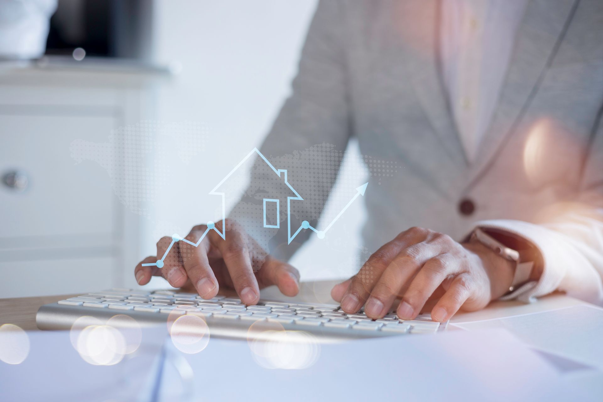 Person typing on keyboard, with a house-shaped graphic overlaid, representing real estate, with rising arrow.
