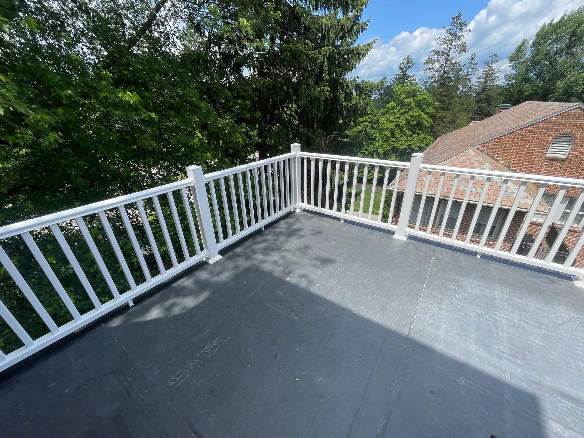 A balcony with a white railing and a view of a house. new roof omni-roof.com