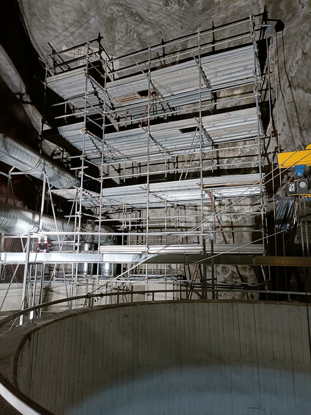 Piattaforma di impalcatura in una grande struttura circolare interrata. La struttura metallica sostiene più livelli.