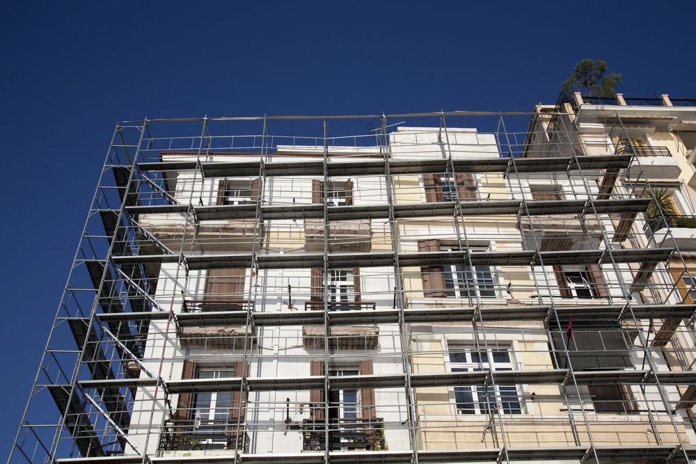 Edificio in fase di ristrutturazione con impalcature contro il cielo azzurro.