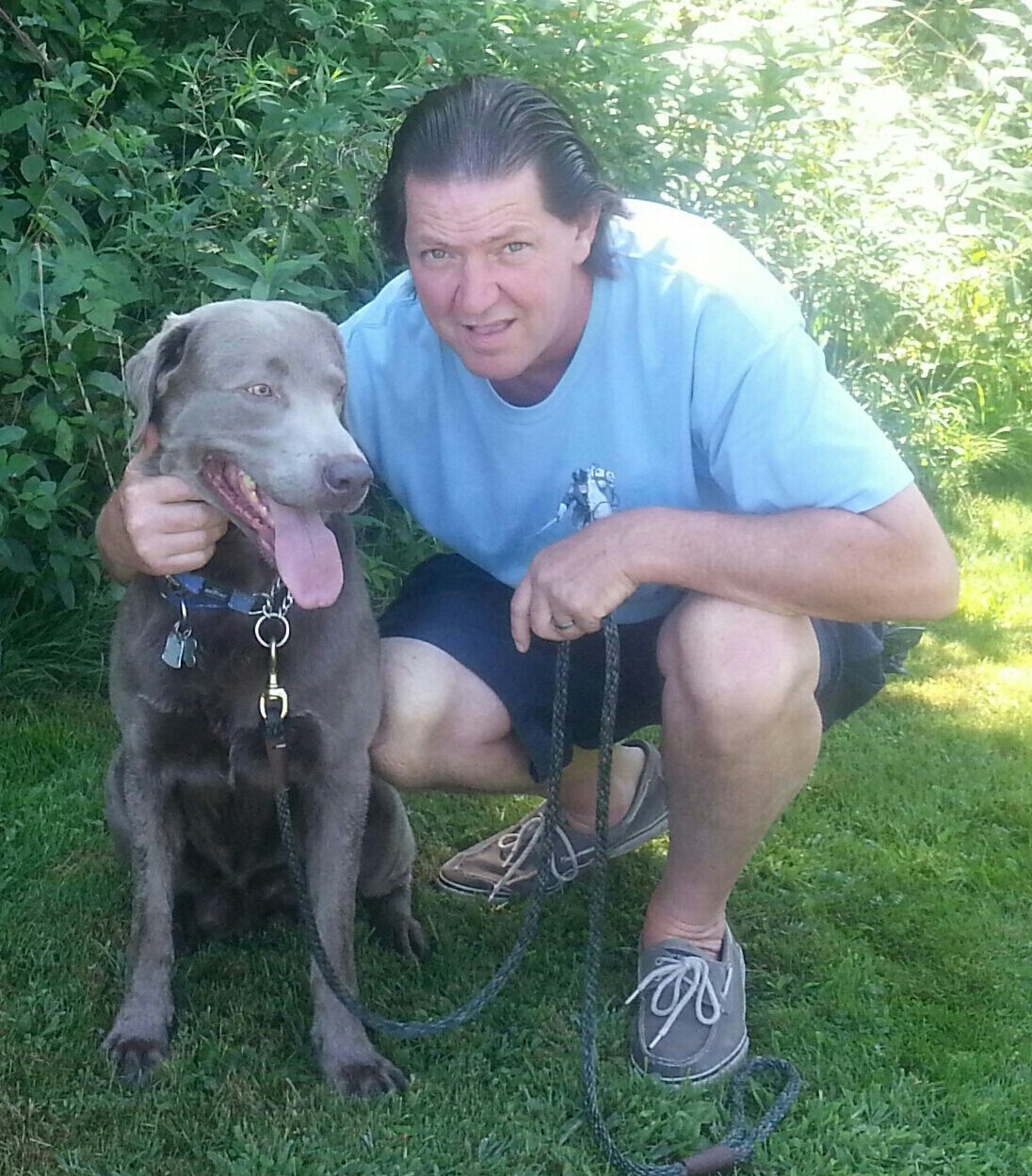 A man kneeling down next to a dog on a leash