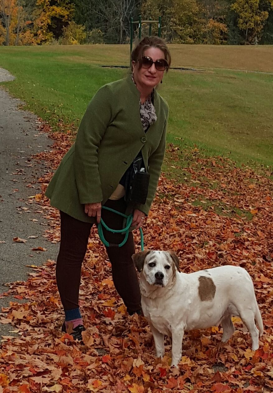 A woman standing next to a white dog on a leash