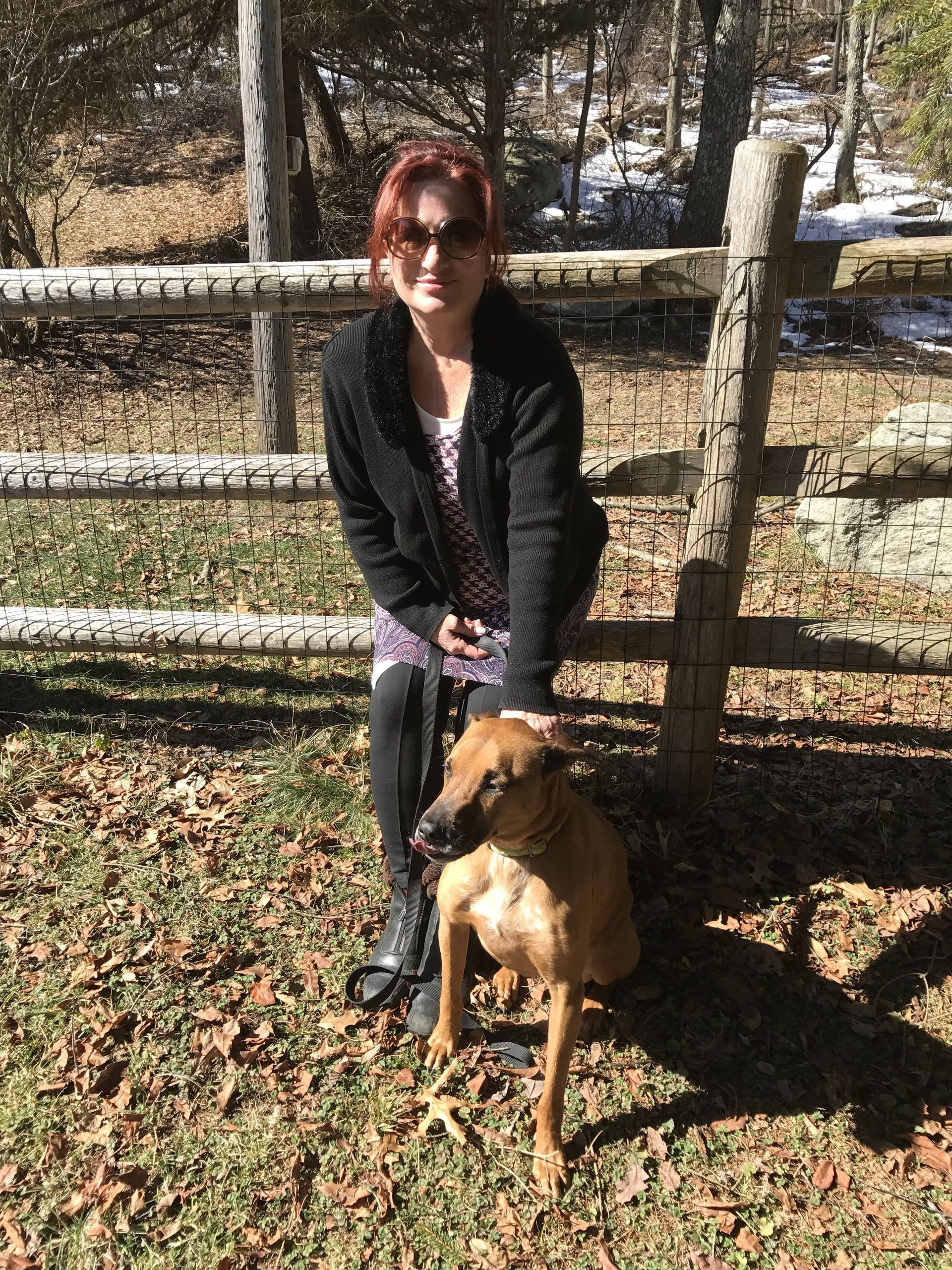 A woman is sitting on a bench next to a dog.
