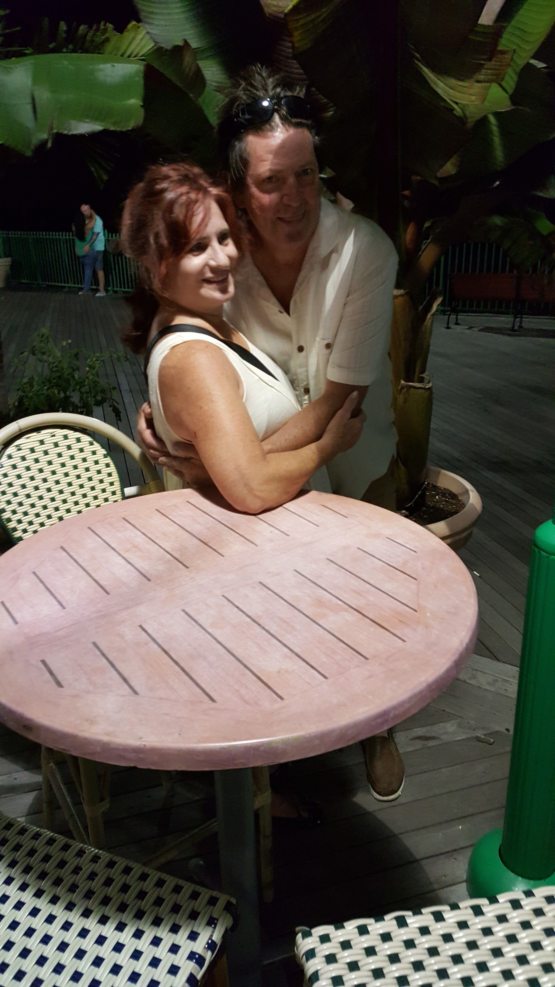 A man is hugging a woman while sitting at a table.