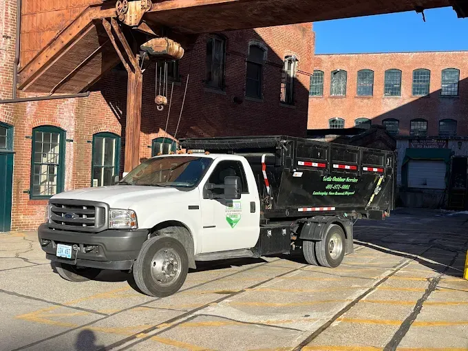 A white dump truck is parked in front of a brick building.