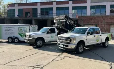 Two trucks and a trailer are parked in front of a building.