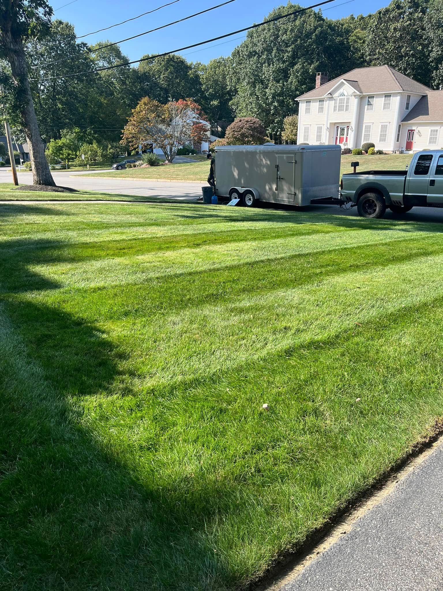 A truck is parked in the grass next to a trailer.