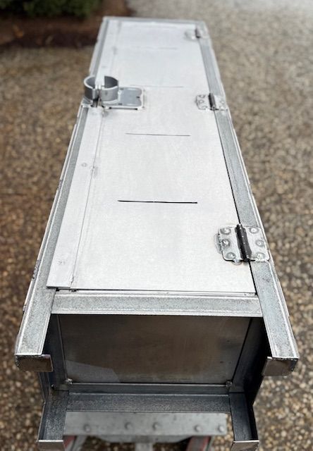 A stainless steel box is sitting on top of a wooden table.