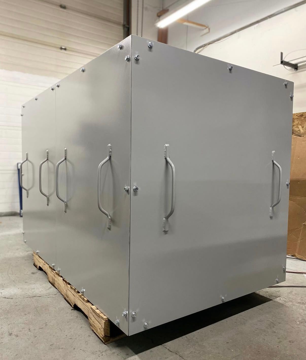 A large metal box is sitting on top of a wooden pallet in a warehouse.