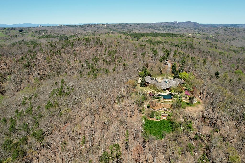 An aerial view of a house in the middle of a forest.