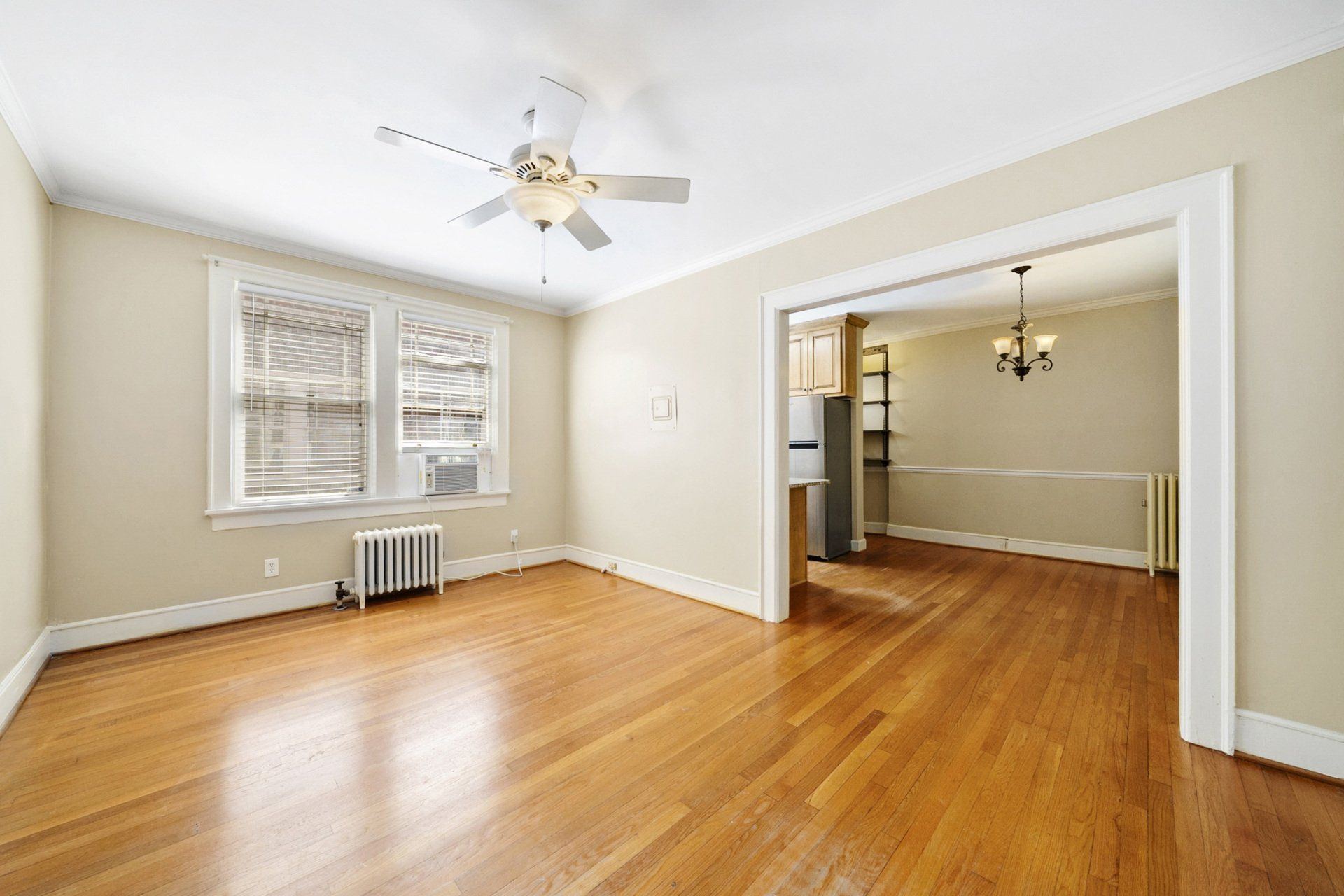 An empty living room with hardwood floors and a ceiling fan.