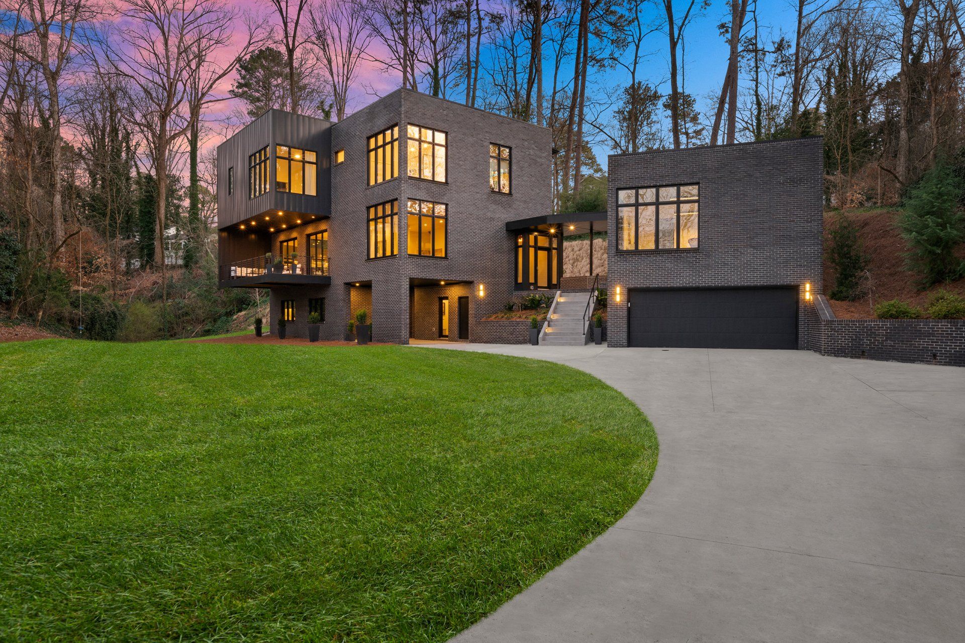 A large house with a lot of windows is surrounded by trees and grass.