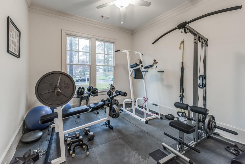 A home gym with a lot of equipment and a ceiling fan.
