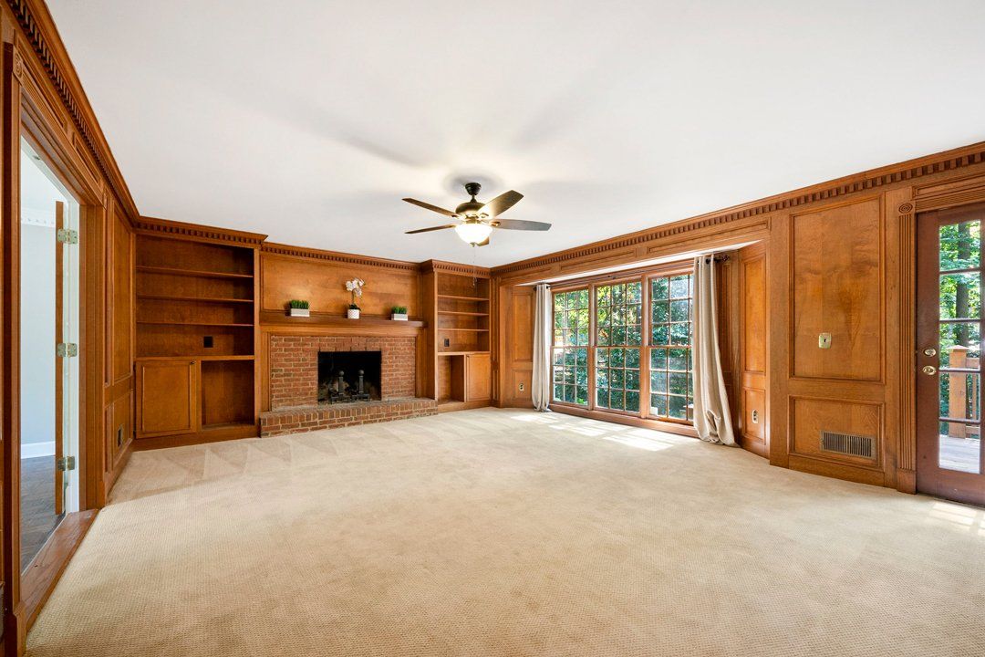 An empty living room with a fireplace and a ceiling fan.