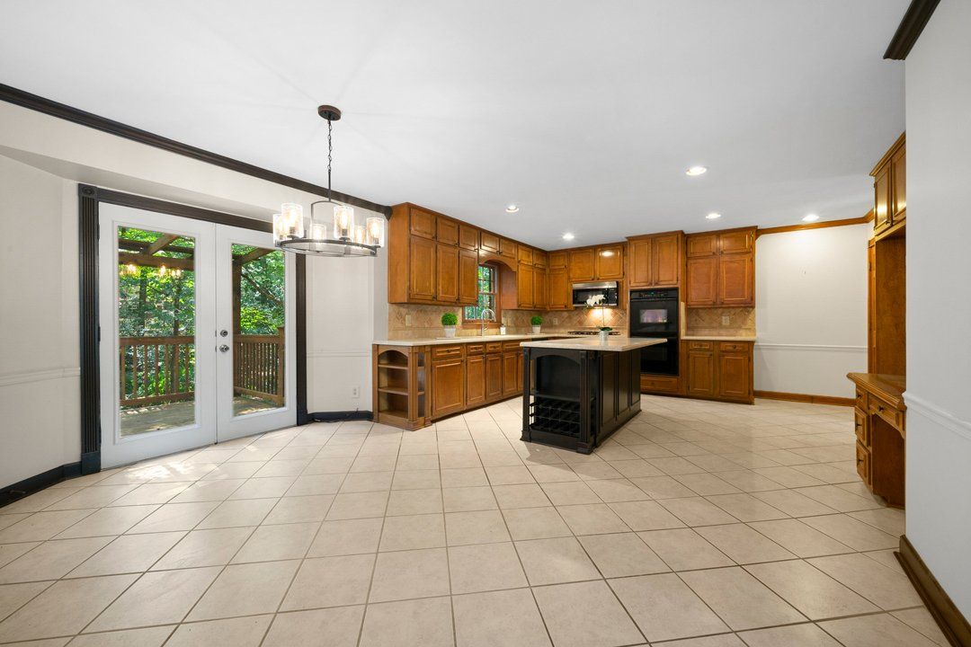 An empty kitchen with wooden cabinets and a tiled floor.