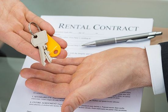 Hands exchange keys over a Rental Contract.