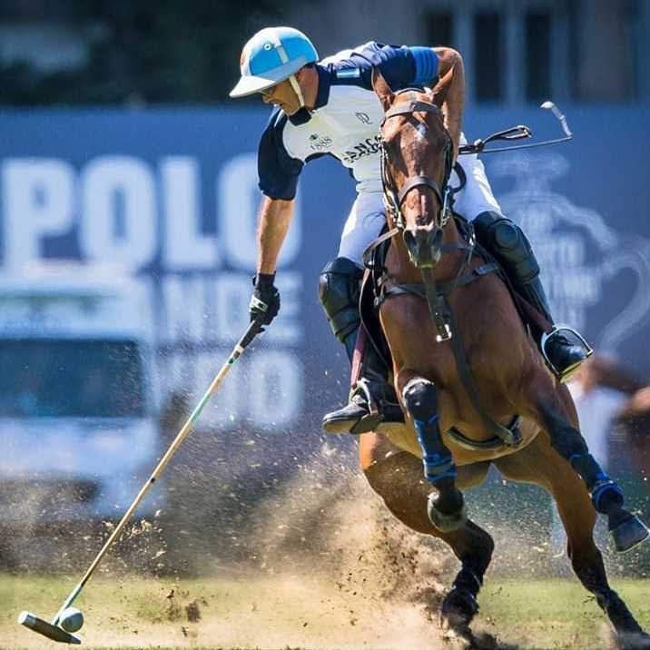 a man is riding a horse while holding a polo stick