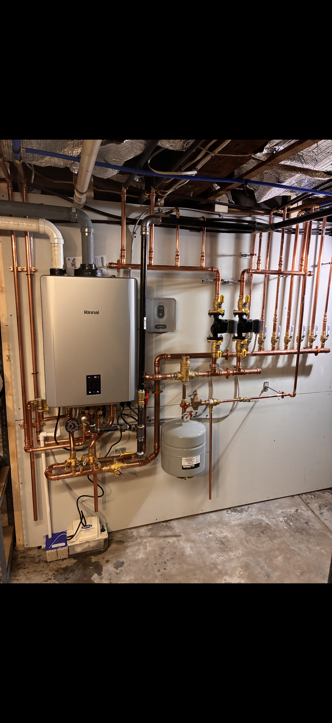 Copper pipes and a water heater installed in a basement.