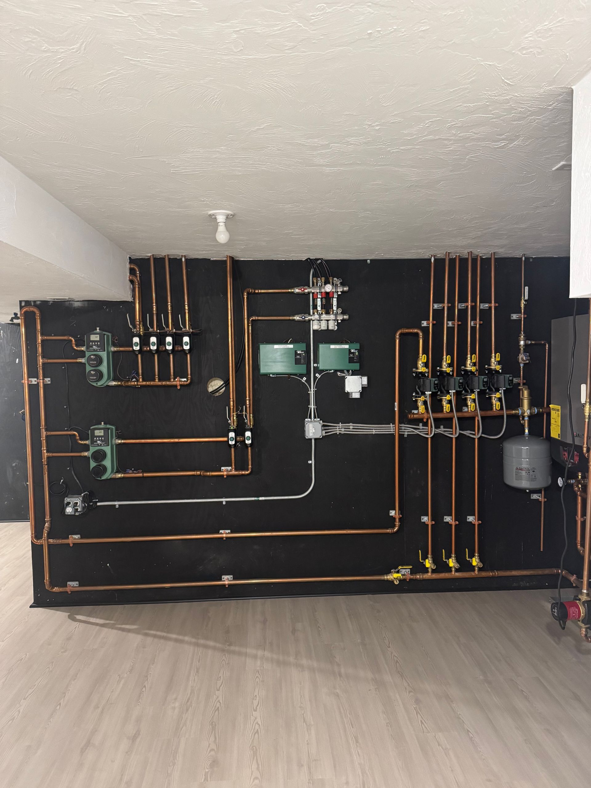 Copper pipes and valves against a black wall.