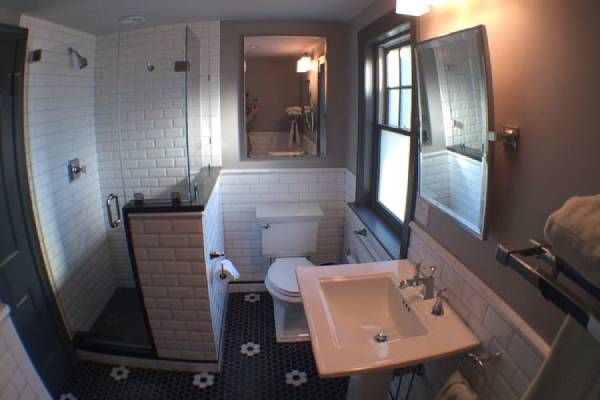 Small bathroom with white subway tile, black and white floor, glass shower, and vanity.