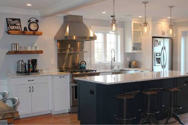 Modern kitchen with white cabinets, blue island, stainless steel range hood, and open shelving.