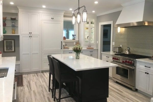 Modern kitchen with white cabinets, dark island, stainless steel appliances, and bar seating.