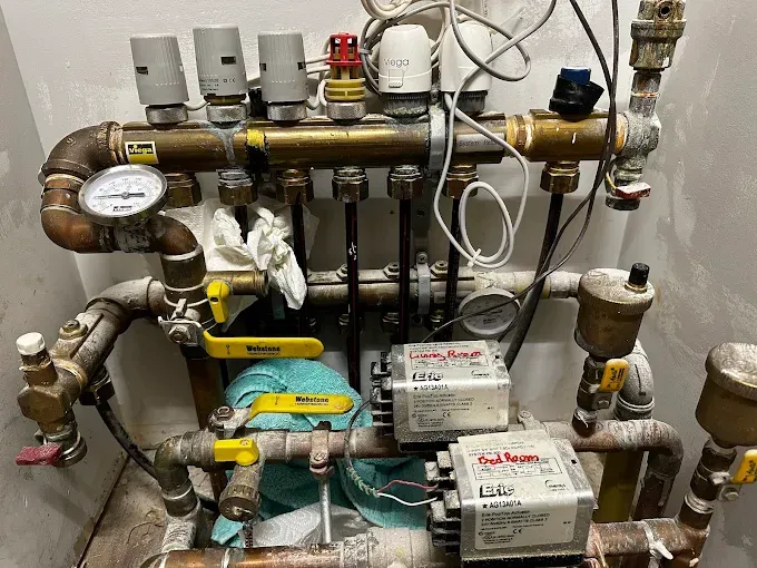 Plumbing system with brass pipes, valves, pressure gauges, and electrical components.