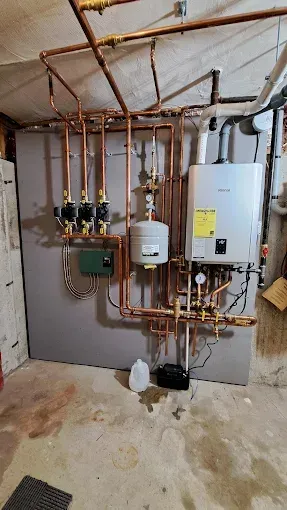 Copper pipes and boiler system in a basement setting.