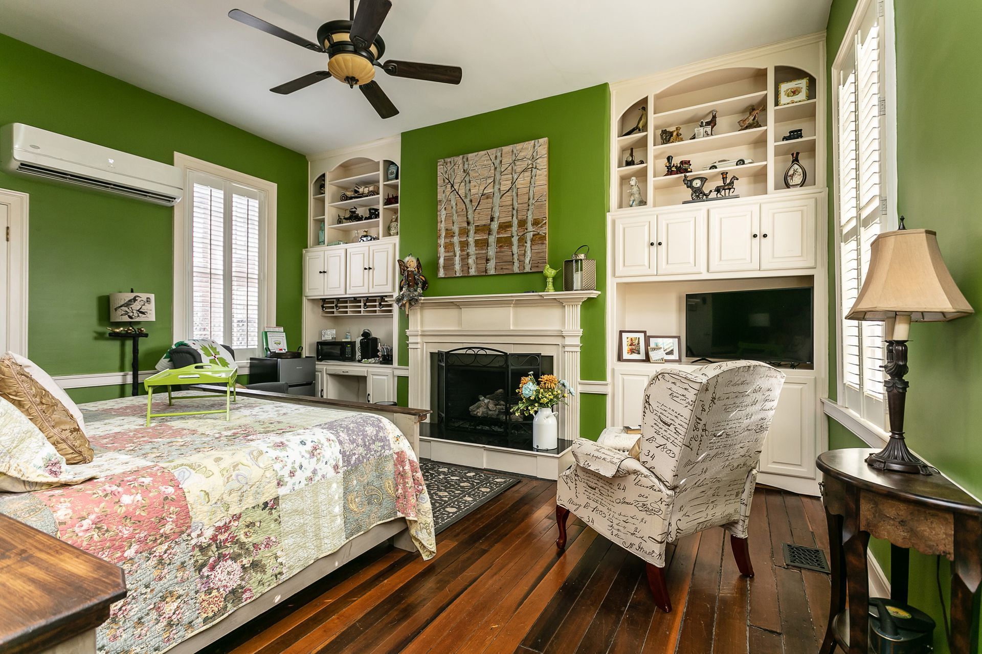 A bedroom with green walls and a fireplace.