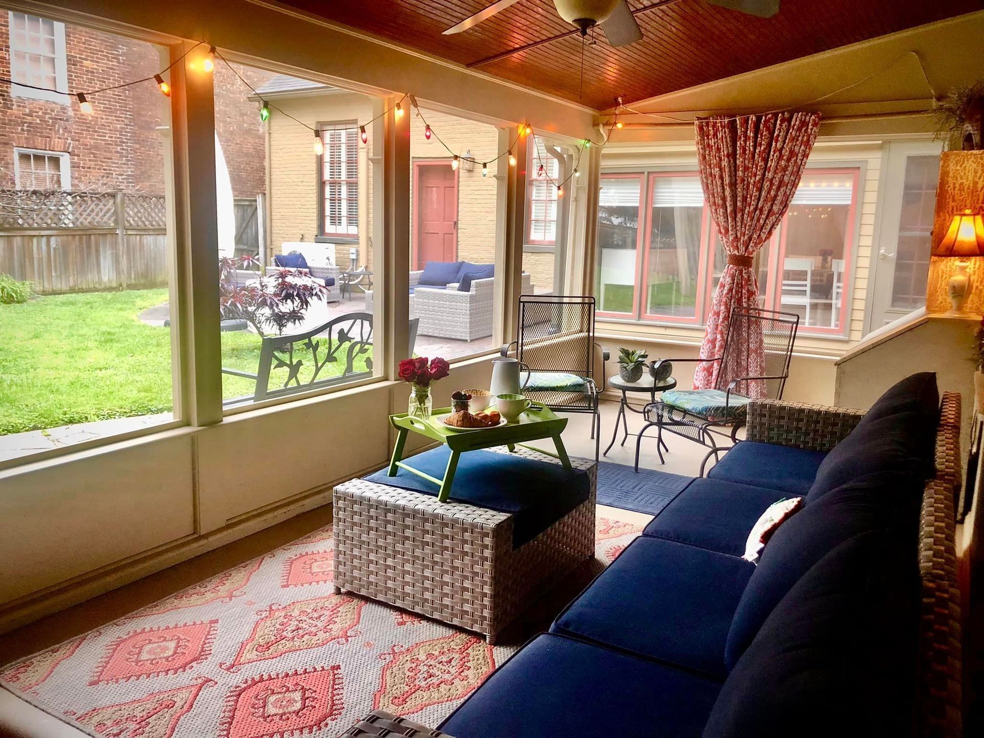 A screened in porch with a blue couch , ottoman , table and chairs.