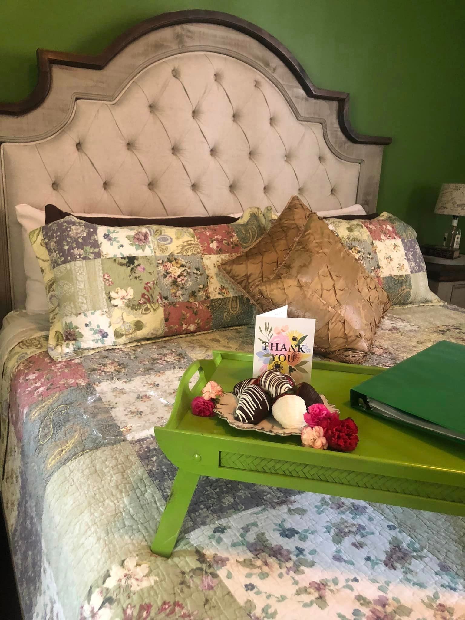 A bed with a green tray on it and a thank you card on it.