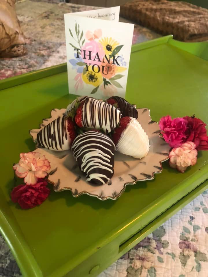 A green tray with chocolate covered strawberries and a thank you card