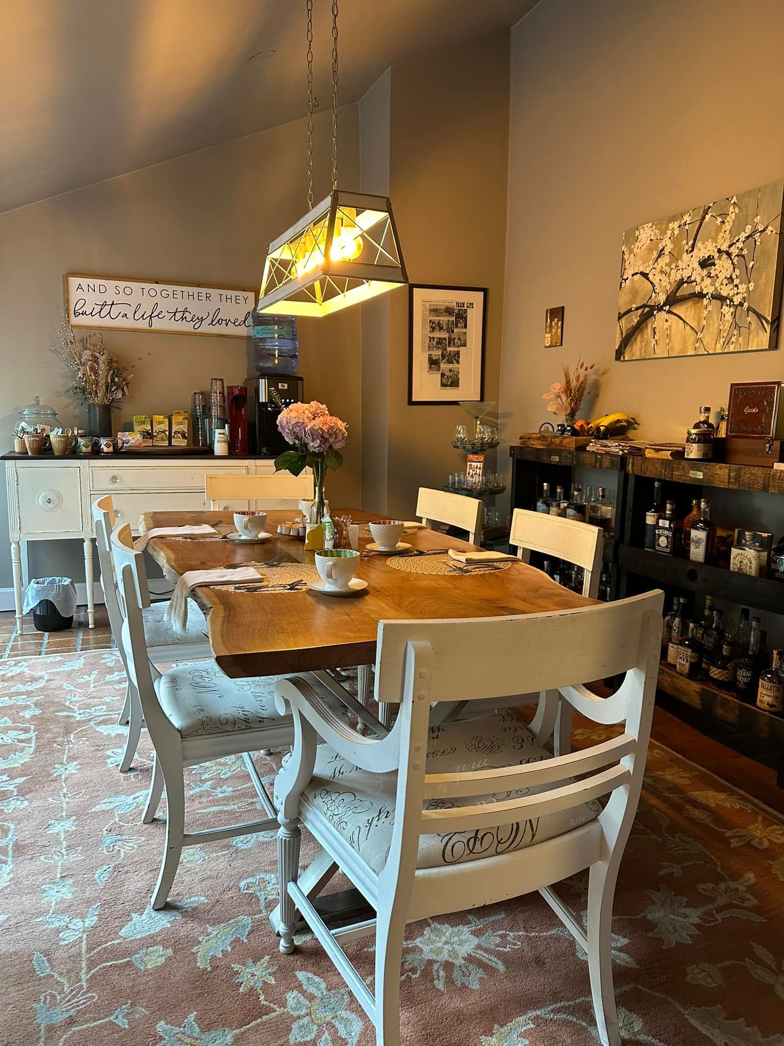 A dining room with a wooden table and white chairs.