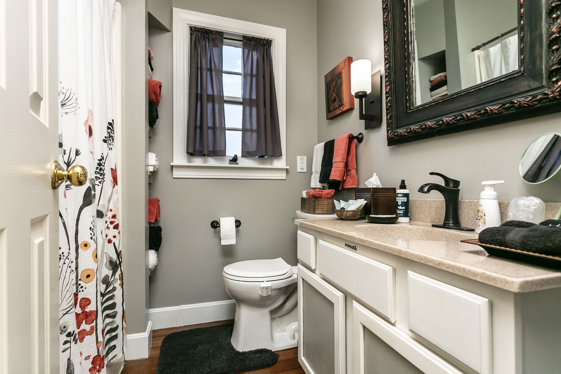 A bathroom with a toilet , sink , mirror and shower curtain.
