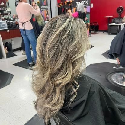 Woman with wavy, highlighted hair in a salon. Hair is light brown and blonde.