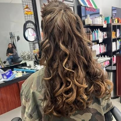 Person with curly brown hair, wearing a camo jacket, in a hair salon.