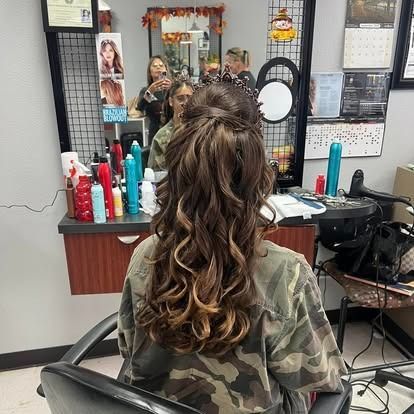 Woman with curled brown hair in a salon chair, styled for an updo. Salon environment .