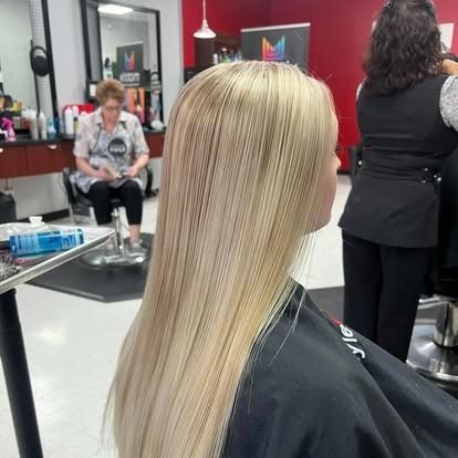 Blond hair being styled at a salon. A woman in a black cape sits in a chair.
