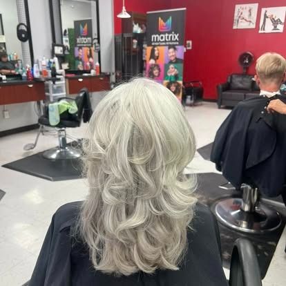 Person with layered, gray hair getting a haircut in a salon.