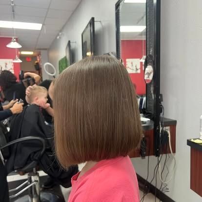 Girl with a sleek, shoulder-length, brown bob haircut, in a hair salon.