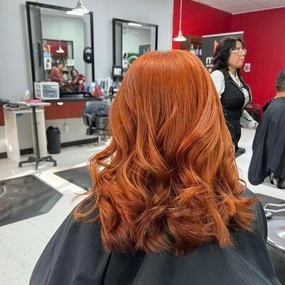 Woman with vibrant red wavy hair in a salon.