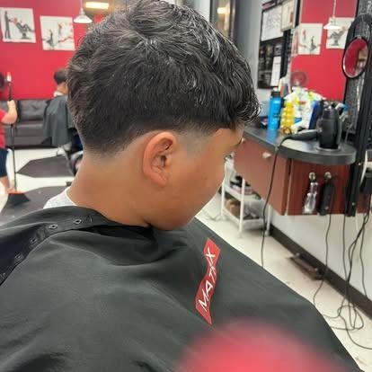 Person at a barber shop, getting a fade haircut. The setting is a barbershop.