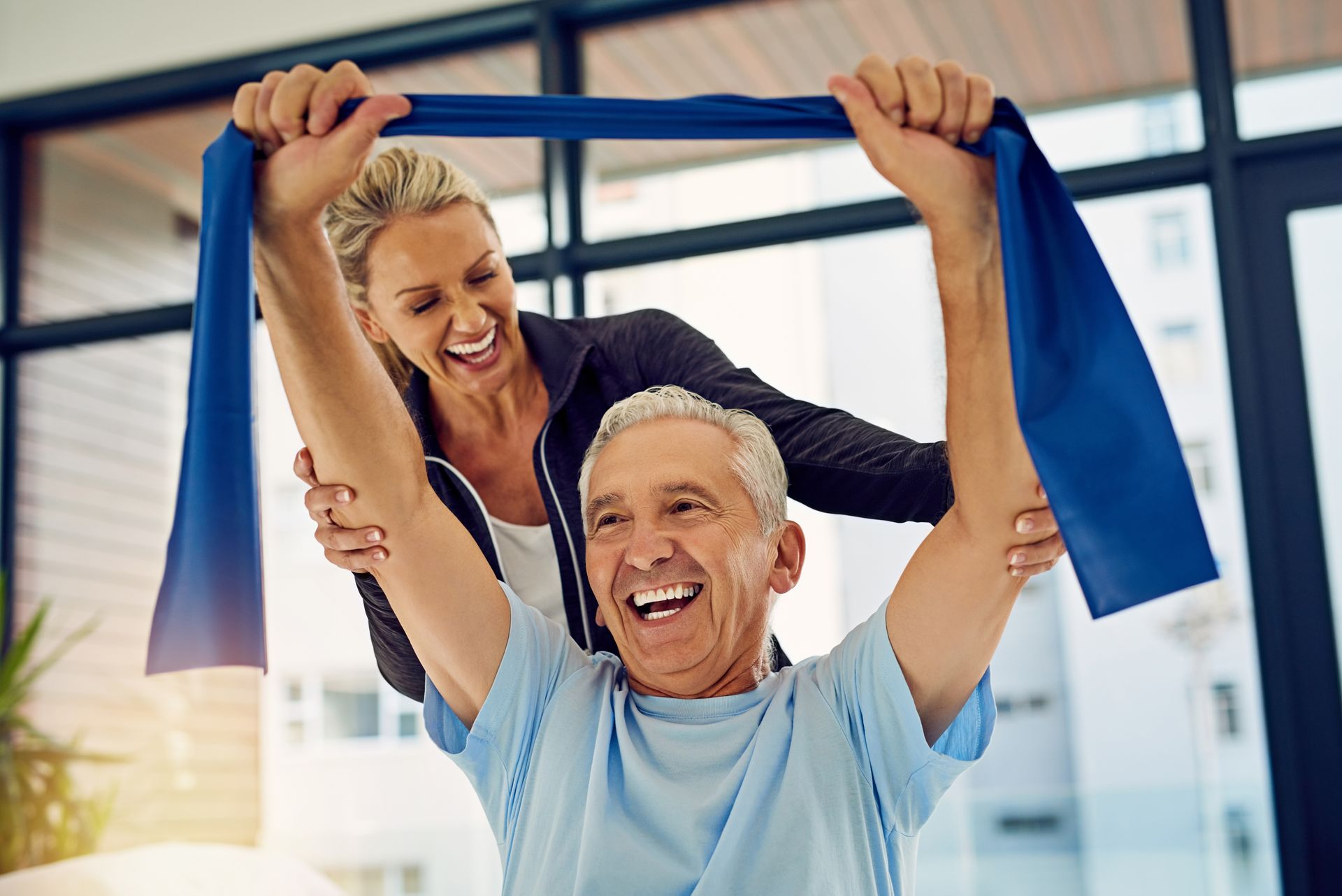 A woman is helping an older man with a resistance band.